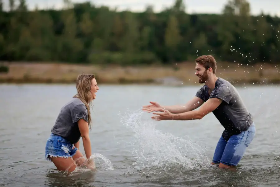 A happy couple playing in the water on a sunny beach, strengthening their bond through Fun Activities for Couples