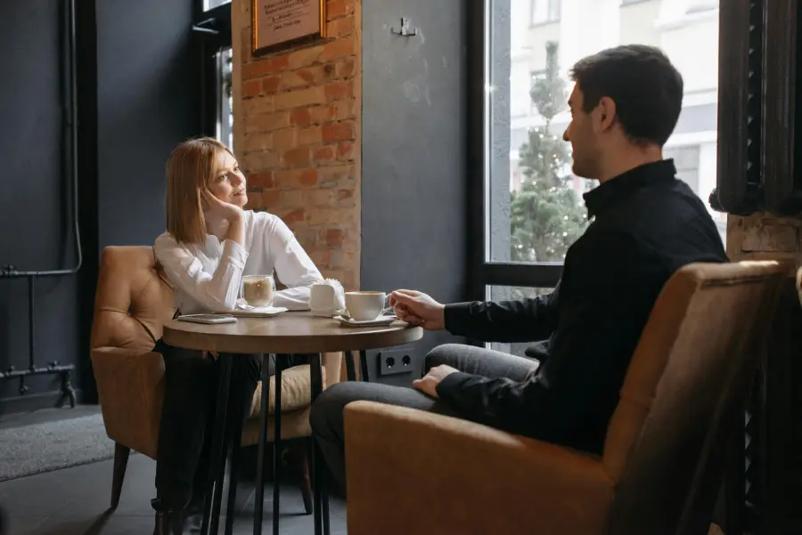 Couple enjoying their first date in a cozy café, sharing a coffee and having a pleasant conversation. Ideal scene for first date advice.