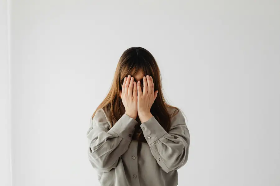 A shy young woman hiding her face, illustrating shyness in romantic relationships