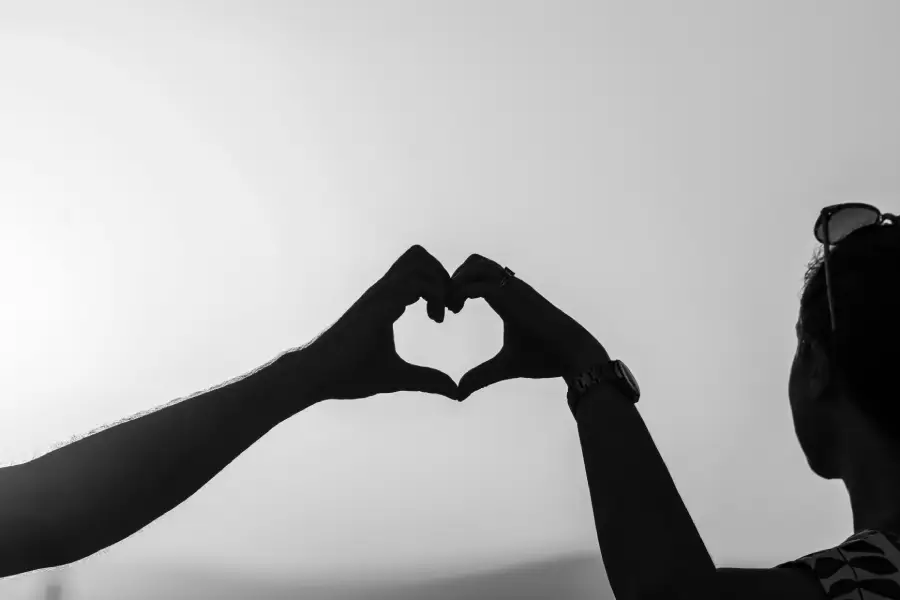 Couple forming a heart shape with their hands, symbolizing love and affection for her