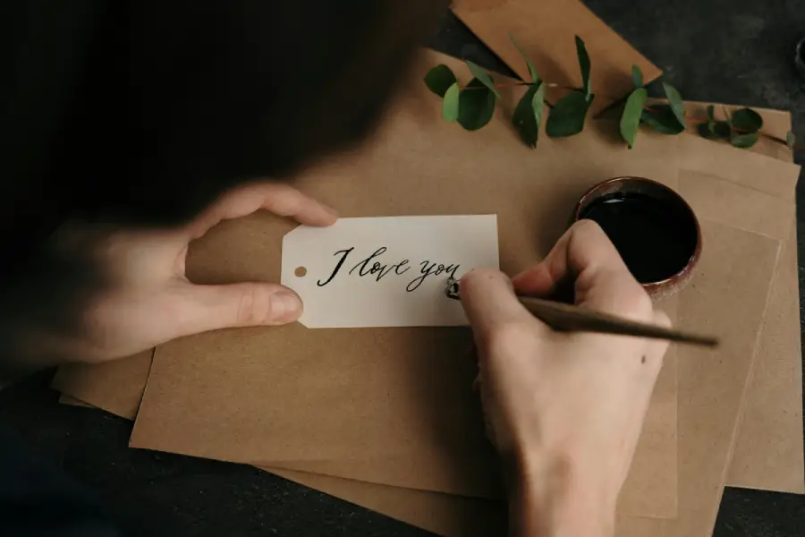 A man writing 'I LOVE YOU', expressing deep love and affection in a romantic message for her