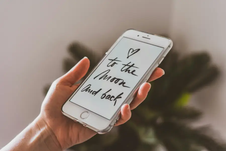 A man receiving a romantic text on his phone saying 'To the moon and back', symbolizing Short Love Messages for Him